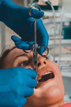 The dentist with the help of a carpule syringe injects anesthesia into the patient's gums, local anesthesia.2020