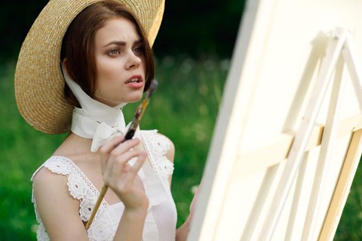 woman artist in hat with brush paints a picture. High quality photo