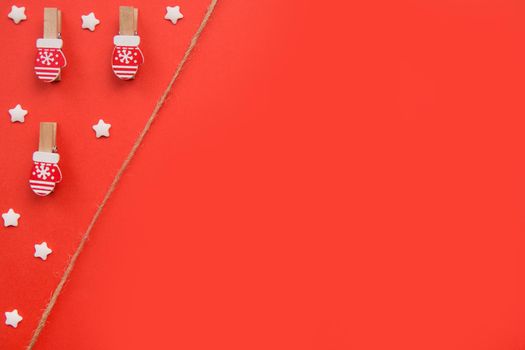 Christmas decorations decorative background. Decorative pins in the form of red gloves on a red background. Top view, minimalism, flat lay. Space for text.