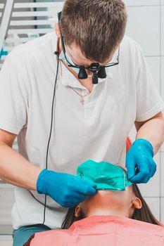 Installation of a rubber dam with a metal clamp for dental fillings, sterile and modern dental treatment.2020