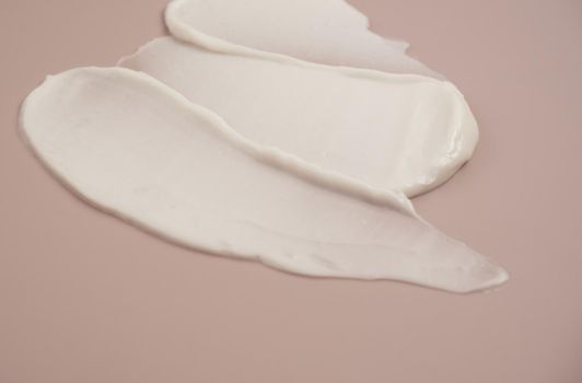 White beauty cream lotion highlighter smear swatch smudge on pink background.