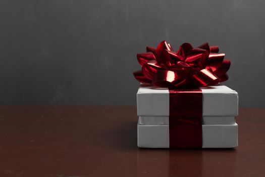 Gift box with a red bow on a wooden table