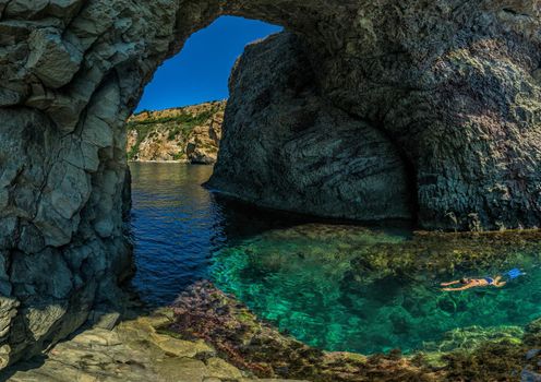 girl dive in the Diana's grotto Sevastopol. Fiolent, Crimea on a background of rocky shores. The concept of an travel, relax, active and healthy life in harmony with nature.