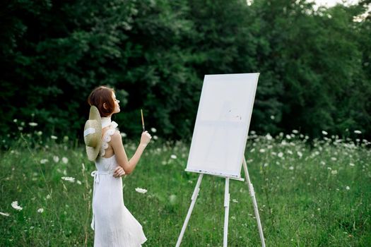 Woman in white dress paints a picture outdoors hobby creative. High quality photo