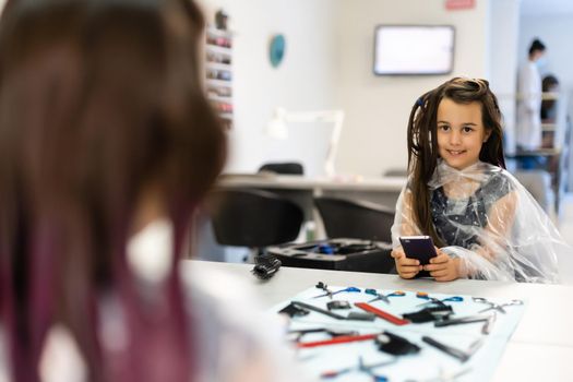 little girl dyes her hair purple in a hairdressing salon