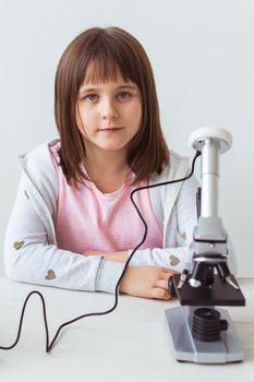 Schoolgirl using microscope in science class. Technologies, lessons and children.