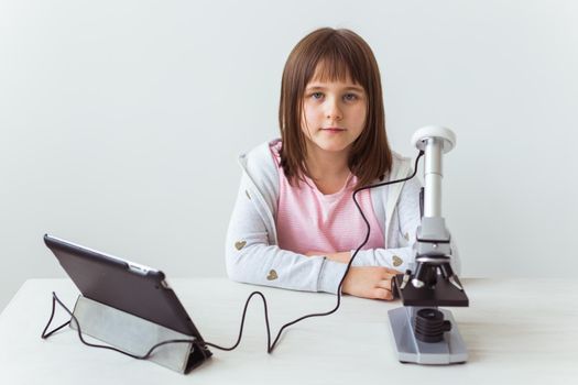 Portrait of cute little child doing homework with a digital microscope Technologies, science and children.