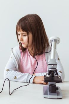 Portrait of cute little child doing homework with a digital microscope Technologies, science and children.