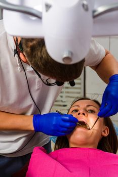 The dentist examines the oral cavity before treating the problem areas of the teeth.2020