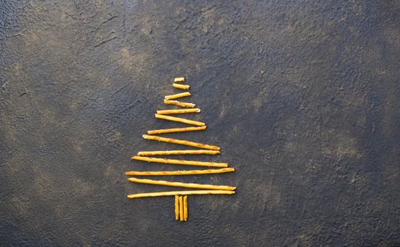 Christmas tree made from pepero straws cookies, on black texture background. View from above