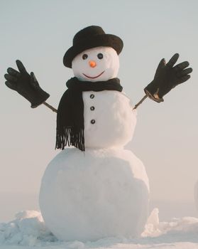 Snowman with hat and scarf in winter outdoor. Snowman gentleman in winter black hat, scarf and gloves. Christmas and winter