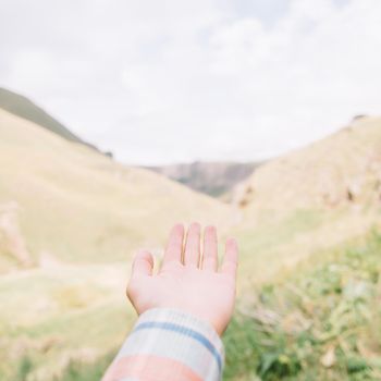 Female hand pointing at mountain valley in summer.