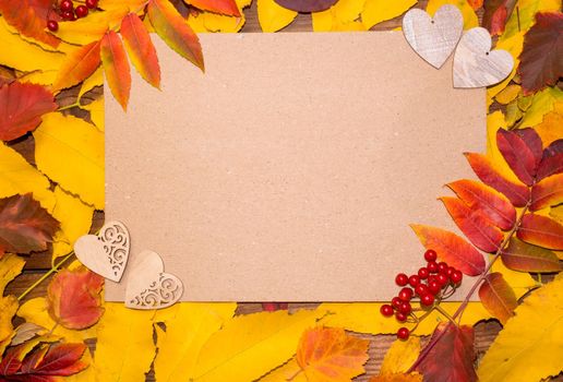 Hello October. Autumn composition, top view of autumn bright colorful leaves with a sheet of paper and wooden two hearts. space for text.