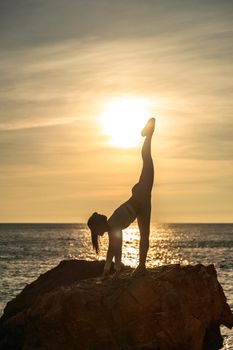 Girl gymnast is training on the beach by the sea sunset. Does twine. Photo series