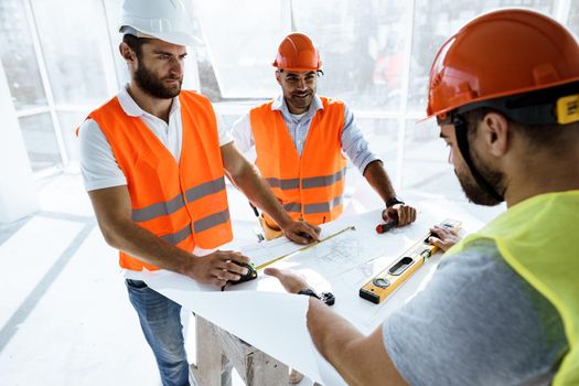 Two young engineers man looking at project plan on the table in construction site