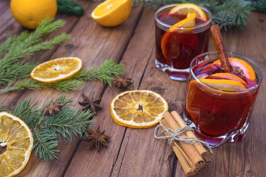 Mulled wine and spices on a wooden background with branches of a Christmas tree. Selective focus.