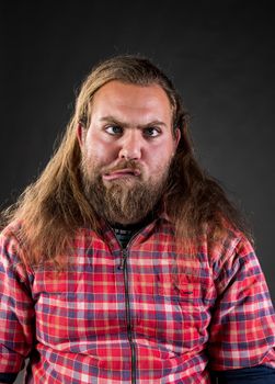 Man with beard and long hair making silly cross eyed face  in studio