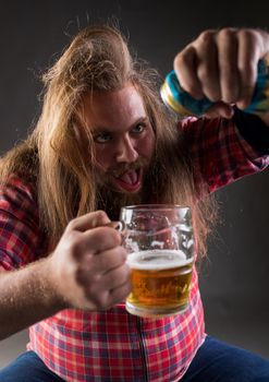 Messy drunk man pouring beer from can into mug in studio