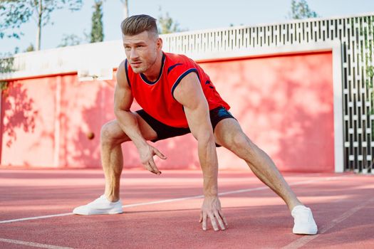 sports man in a red t-shirt on the sports ground doing exercises. High quality photo