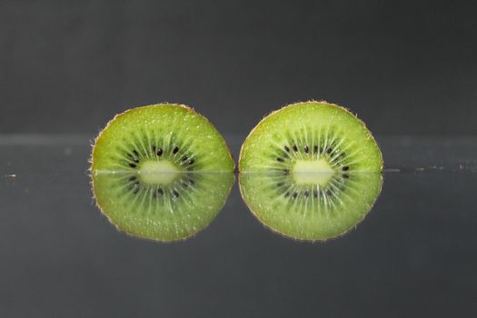 two or three circles of green kiwi semicircle with a black glossy still life.
