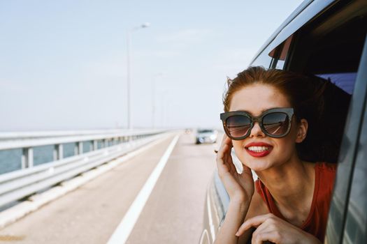 a woman is driving in a car on the road and looking out of the window. High quality photo