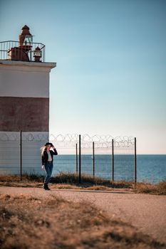 A blonde in a stylish black leather jacket walks along the seashore