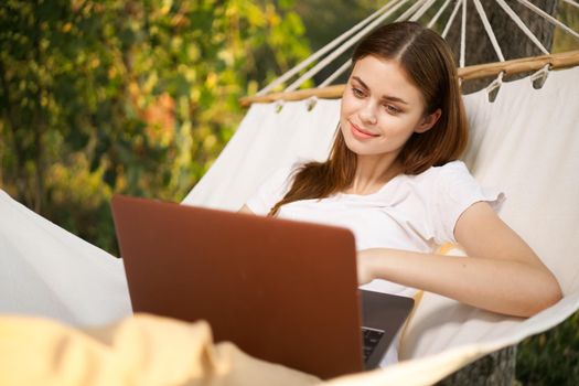 woman with laptop lies in hammock freelance travel. High quality photo