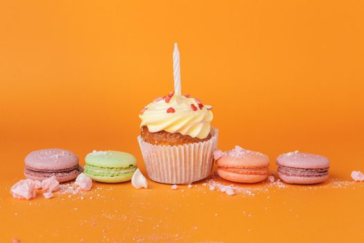 Cupcake with birthday candles on orange background