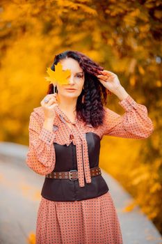 Beautiful girl walking outdoors in autumn. Smiling girl collects yellow leaves in autumn. Young woman enjoying autumn weather