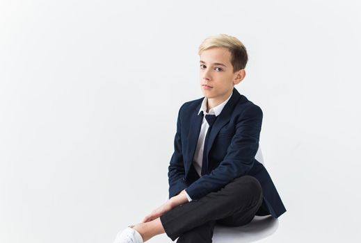 Portrait of stylish school boy teenager in white shirt and jacket against white background with copy space