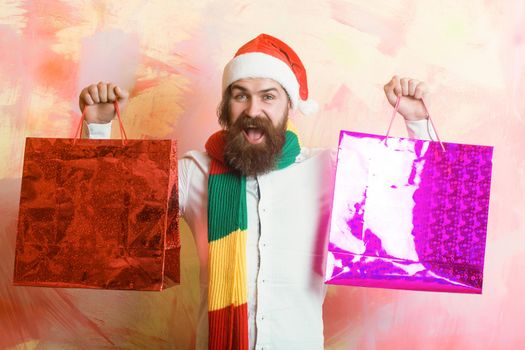 Happy man with beard in red santa hat with shopping bag