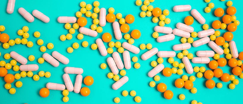 different colorful and white pills, capsules. Prevention, cure of influenza, coronavirus, covid-19. yellow, orange vitamins, tablets on blue background. medical healthcare, protection concept banner