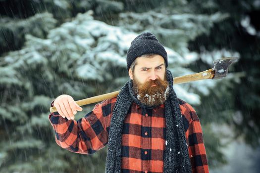 Serious man lumberjack with axe outdoor in winter.