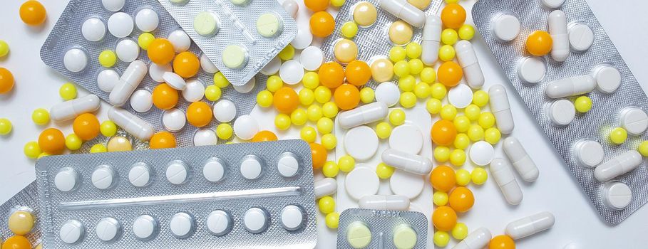 different colorful and white pills, capsules. Prevention, cure of influenza, coronavirus, covid-19. yellow, orange vitamins, tablets on white background. medical healthcare, protection concept banner
