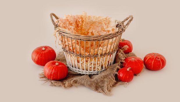 Tiny basket for newborn studio photoshoot decorated with pumpkins and sackcloth. Cute decoration for infant child kid photos
