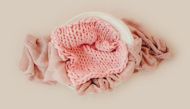 Tiny basin for newborn girl studio photoshoot decorated with pink knitted blanket. Cute decoration for infant child kid photos