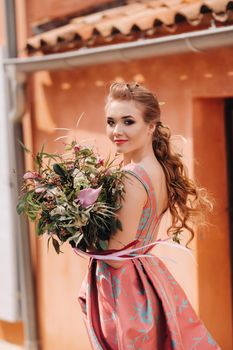 A young model girl in a beautiful dress with a bouquet of flowers in the countryside in France. Girl with flowers in the spring Provence village