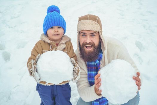 Winter, father and son play outdoor. Happy child playing with snowball against white winter background