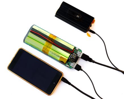 Charging the flashlight and phone through the disassembled Power Bank. Disassemble and test the operation of the portable battery device.