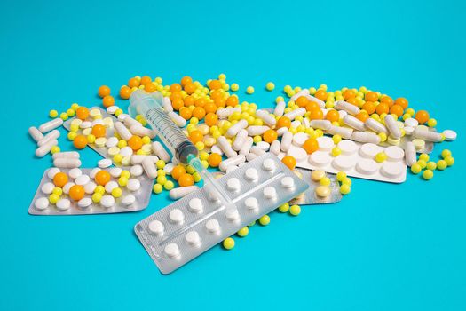 colorful and white pills, capsules, syringe. Prevention, cure of influenza, coronavirus, covid-19. yellow, orange vitamins, tablets on blue background. medical healthcare, protection concept banner