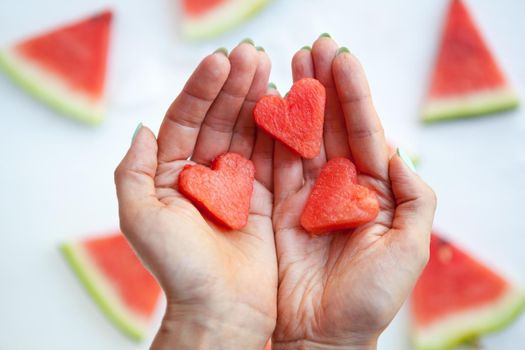 Watermelon hearts slices on womans hands. Sliced watermelon on white background. Flat lay, top view. watermelon slices on white. Love and care concept