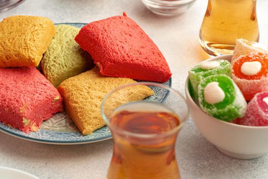 Various Turkish sweets and cup of tea on white textured background, close up