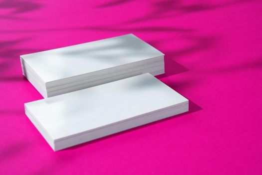 Advertising mock-up. White blank businesscards on bright pink background. copy space