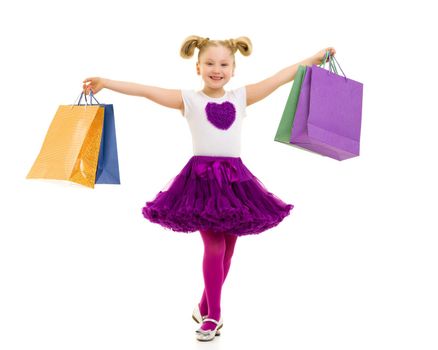 A cheerful little girl is shopping in a store with large, multi-colored paper bags. The concept of holidays, advertising sales. Isolated on white background.