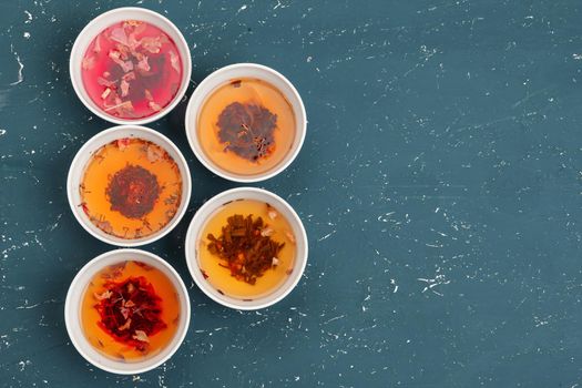 Tea concept. Different kinds of dry tea in ceramic bowls and cups of aromatic tea