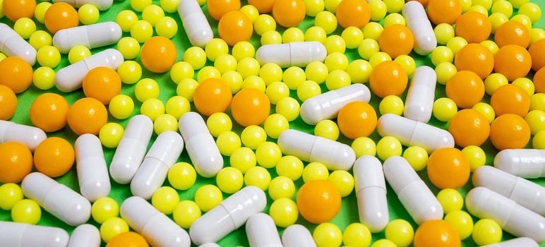 different colorful pills, capsules. Prevention, cure of influenza, coronavirus, covid-19, 2019-nCoV. yellow, orange vitamins, tablets on green background. medical healthcare, protection concept banner