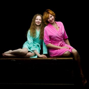 Daughter and mother in bath robes in a photo studio. The concept of relaxation, cosmetics. Isolated