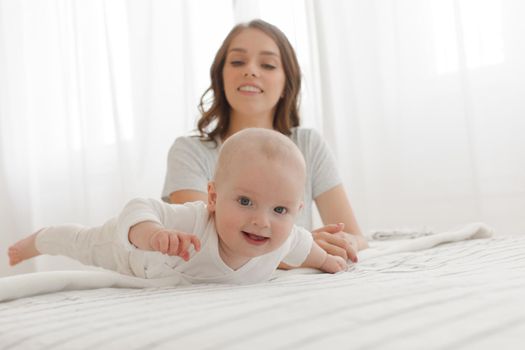 happy family. Mother and baby playing and smiling on the bed