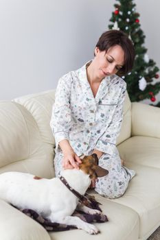 Happy young woman with lovely dog in living room with christmas tree. Holidays.