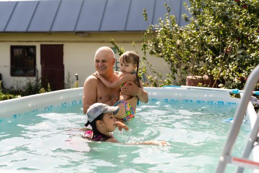 Portrait of a happy grandfather with grandchildren in pool